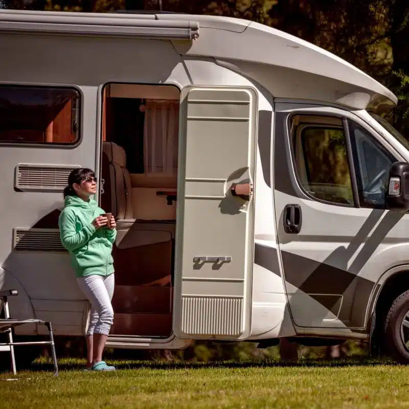 Lady standing outside RV with coffee